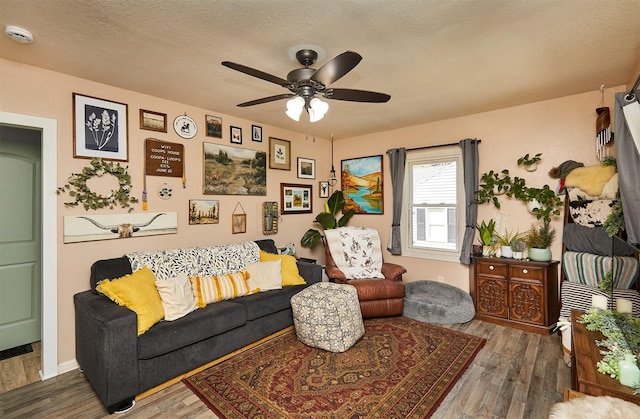 living area featuring ceiling fan, wood finished floors, and a textured ceiling