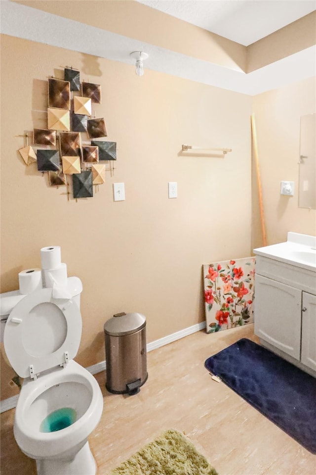 1424 Cleveland Ave, Des Moines, IA 50316 - bathroom featuring wood finished floors, baseboards, vanity, and toilet