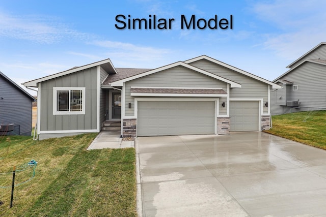 view of front of house with a garage, a front lawn, driveway, board and batten siding, and roof with shingles