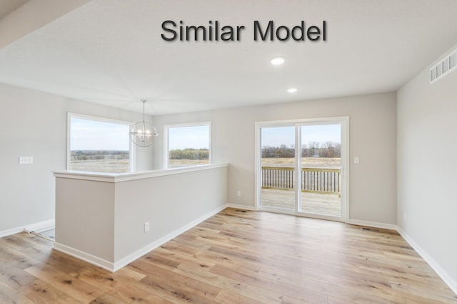spare room with a chandelier, light wood-style flooring, recessed lighting, and baseboards