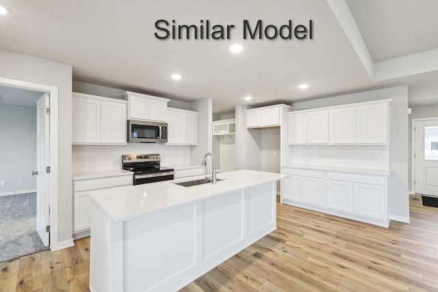 kitchen with stainless steel appliances, a sink, light wood-style floors, white cabinets, and light countertops