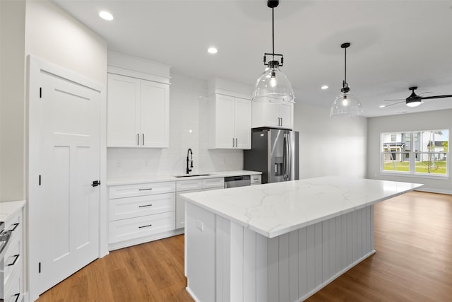1998 S Warrior Ln, Waukee, IA 50263 - kitchen featuring stainless steel appliances, a sink, light wood-style floors, a center island, and decorative backsplash