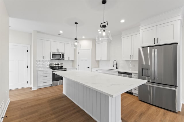 1998 S Warrior Ln, Waukee, IA 50263 - kitchen with appliances with stainless steel finishes, a sink, backsplash, wood finished floors, and a center island
