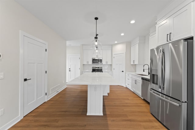 1998 S Warrior Ln, Waukee, IA 50263 - kitchen featuring stainless steel appliances, a sink, a kitchen island, white cabinets, and recessed lighting