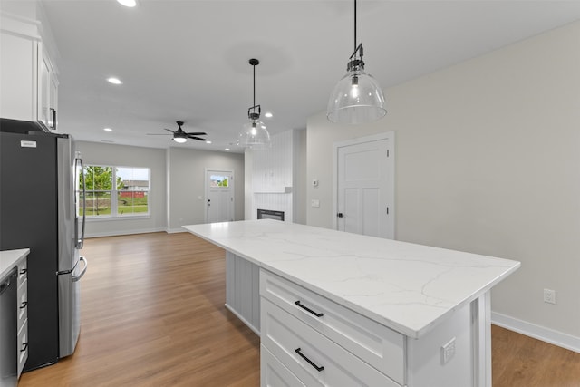 1998 S Warrior Ln, Waukee, IA 50263 - kitchen with freestanding refrigerator, ceiling fan, a kitchen island, white cabinets, and light wood-style flooring