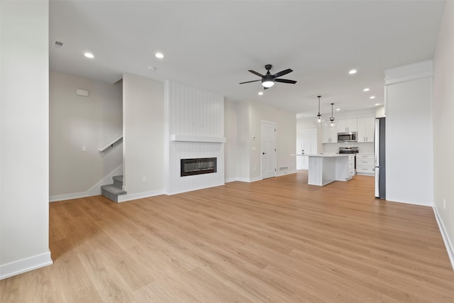 1998 S Warrior Ln, Waukee, IA 50263 - unfurnished living room featuring a large fireplace, recessed lighting, a ceiling fan, stairway, and baseboards