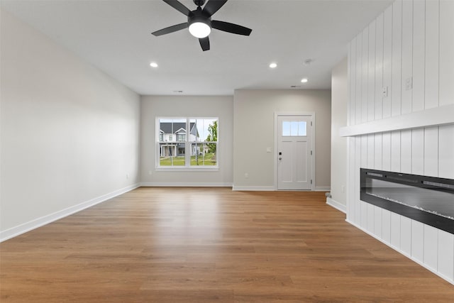 1998 S Warrior Ln, Waukee, IA 50263 - unfurnished living room featuring a ceiling fan, a fireplace, wood finished floors, recessed lighting, and baseboards