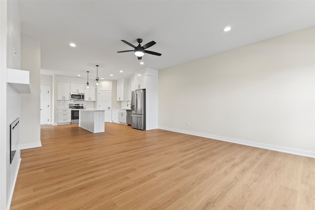 1998 S Warrior Ln, Waukee, IA 50263 - unfurnished living room with ceiling fan, recessed lighting, baseboards, and light wood-type flooring