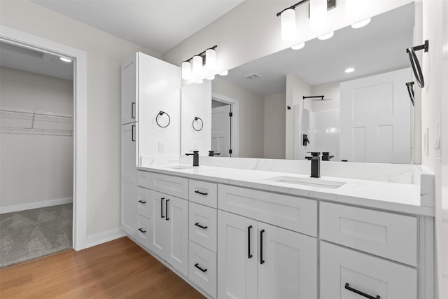 1998 S Warrior Ln, Waukee, IA 50263 - full bath featuring double vanity, a walk in closet, baseboards, wood finished floors, and a shower