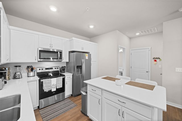 9556 Crestview Dr, West Des Moines, IA 50266 - kitchen featuring stainless steel appliances, wood finished floors, white cabinetry, light countertops, and a sink