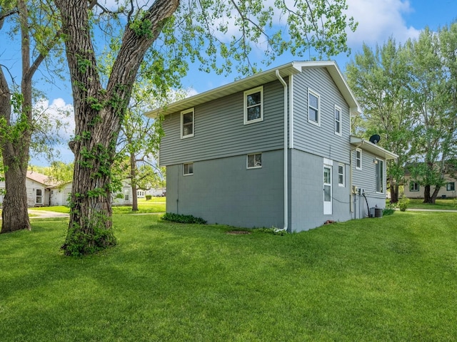 view of side of property with a yard and central AC
