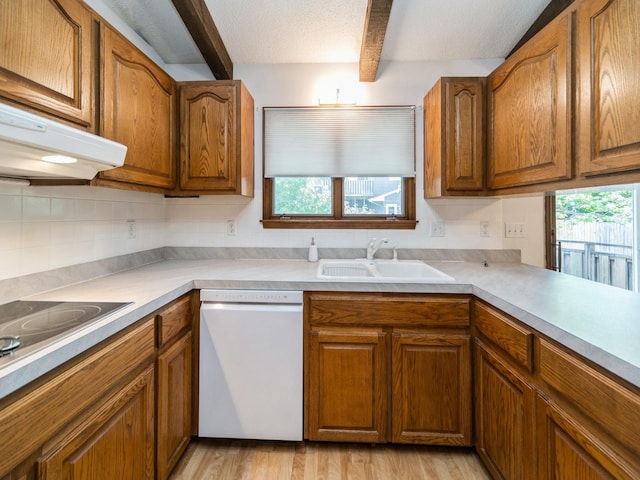 kitchen featuring white dishwasher, a sink, healthy amount of natural light, brown cabinetry, and beam ceiling