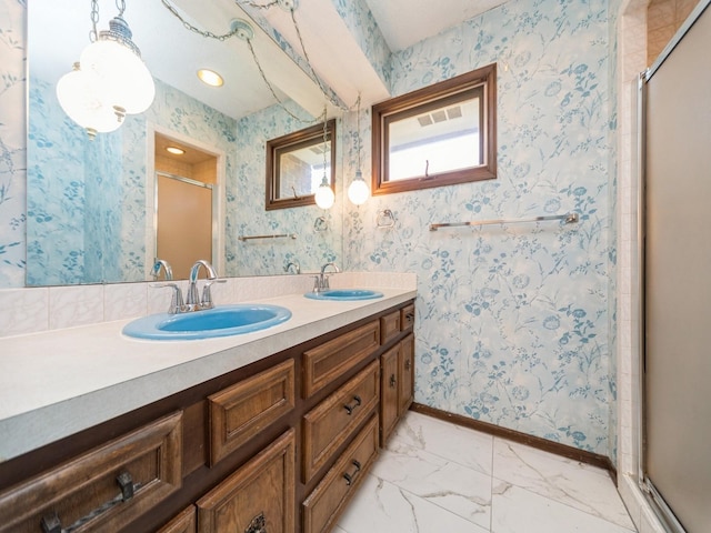 bathroom with a stall shower, double vanity, and baseboards