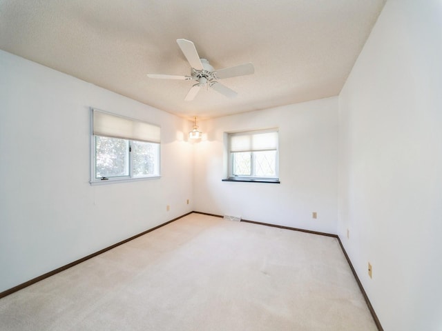unfurnished room with plenty of natural light, carpet floors, baseboards, and a ceiling fan