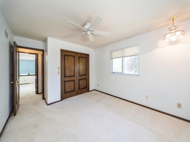 unfurnished bedroom with light colored carpet, baseboards, and ceiling fan