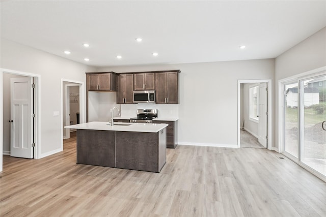 2331 N 8th Ave E, Newton, IA 50208 - kitchen featuring appliances with stainless steel finishes, light wood-style floors, an island with sink, dark brown cabinetry, and recessed lighting