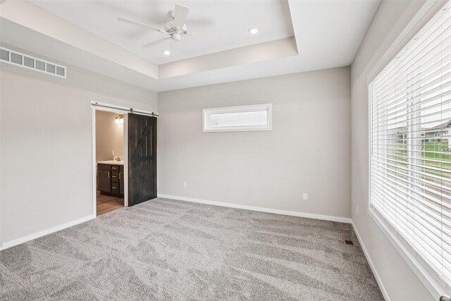 2331 N 8th Ave E, Newton, IA 50208 - unfurnished bedroom featuring a barn door, carpet floors, baseboards, ensuite bathroom, and a ceiling fan