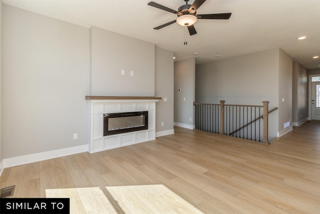 4416 NE 8th St, Ankeny, IA 50021 - unfurnished living room with wood finished floors, recessed lighting, baseboards, a ceiling fan, and a glass covered fireplace