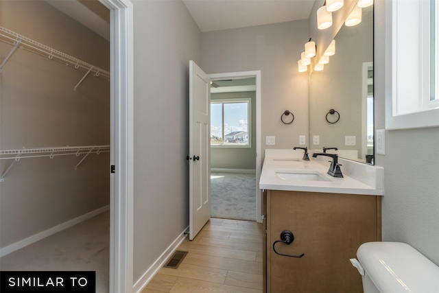 4416 NE 8th St, Ankeny, IA 50021 - bathroom with double vanity, toilet, wood finished floors, baseboards, and a walk in closet