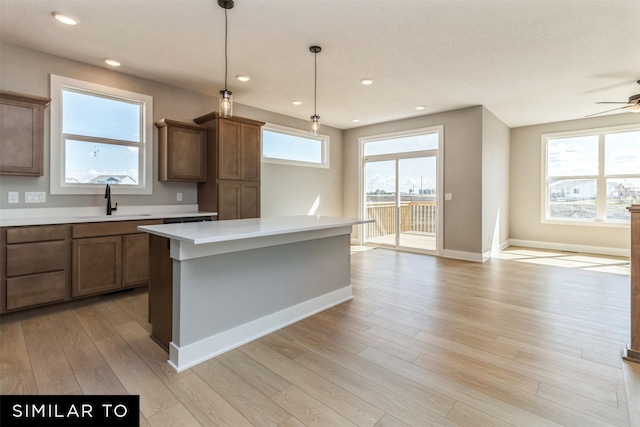 4416 NE 8th St, Ankeny, IA 50021 - kitchen with a sink, light countertops, light wood finished floors, a ceiling fan, and baseboards