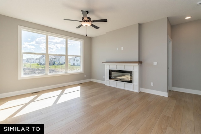 4416 NE 8th St, Ankeny, IA 50021 - unfurnished living room featuring a tiled fireplace, baseboards, light wood-type flooring, and recessed lighting