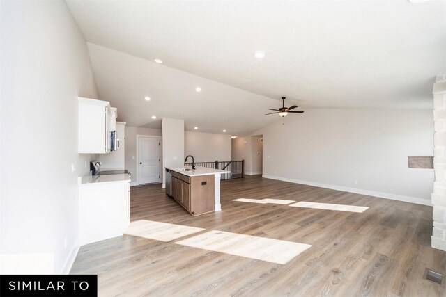 4404 NE 8th St, Ankeny, IA 50021 - kitchen with a ceiling fan, vaulted ceiling, open floor plan, white cabinets, and a center island with sink