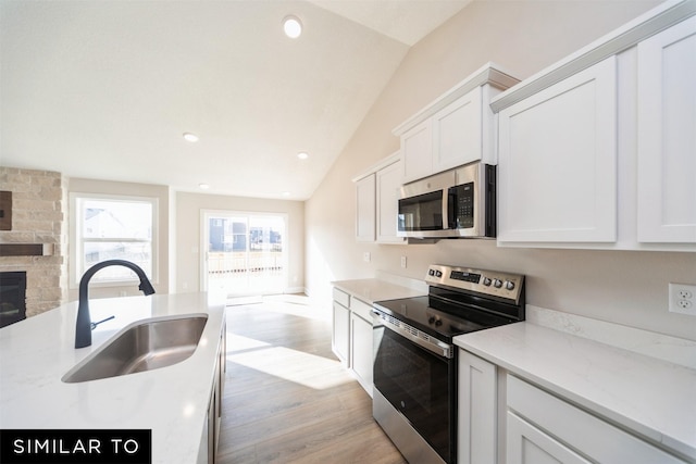 4404 NE 8th St, Ankeny, IA 50021 - kitchen featuring stainless steel appliances, a sink, vaulted ceiling, open floor plan, and light wood-style floors