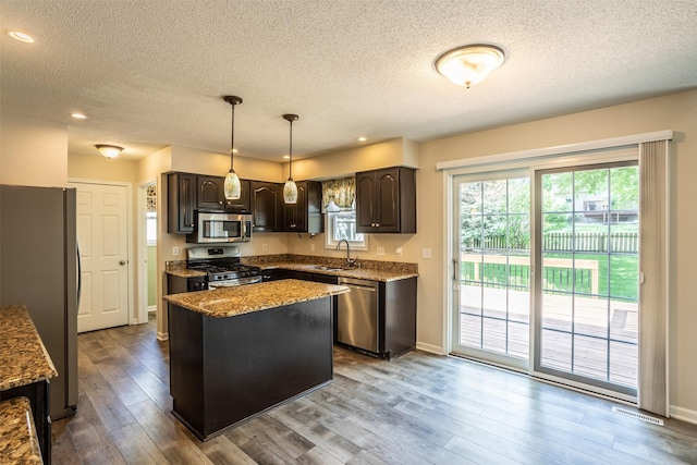 15046 Summit Dr, Clive, IA 50325 - kitchen featuring stainless steel appliances, a textured ceiling, dark brown cabinets, dark wood finished floors, and a kitchen island