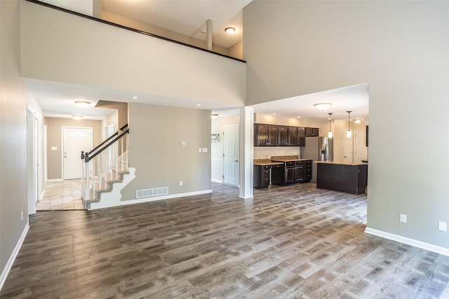 15046 Summit Dr, Clive, IA 50325 - unfurnished living room with wood finished floors, stairway, and a towering ceiling