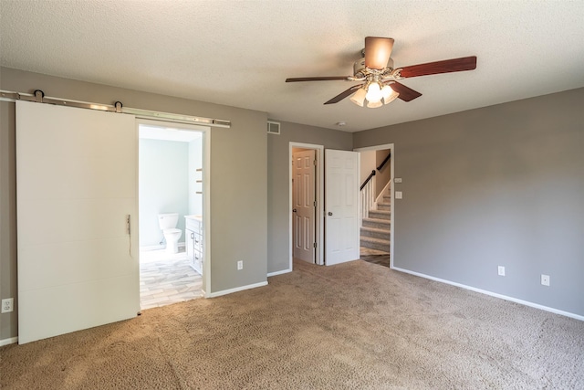15046 Summit Dr, Clive, IA 50325 - unfurnished bedroom featuring carpet flooring, a barn door, connected bathroom, and ceiling fan