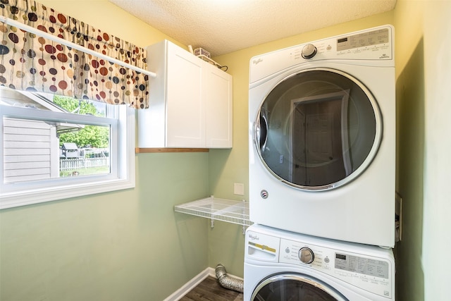 15046 Summit Dr, Clive, IA 50325 - laundry room featuring estacked washer and dryer, cabinet space, dark wood-type flooring, and a textured ceiling