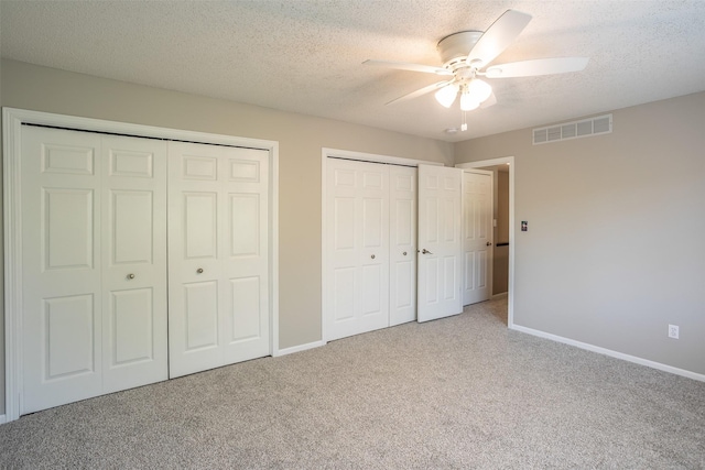 15046 Summit Dr, Clive, IA 50325 - unfurnished bedroom featuring multiple closets, carpet floors, a textured ceiling, and a ceiling fan