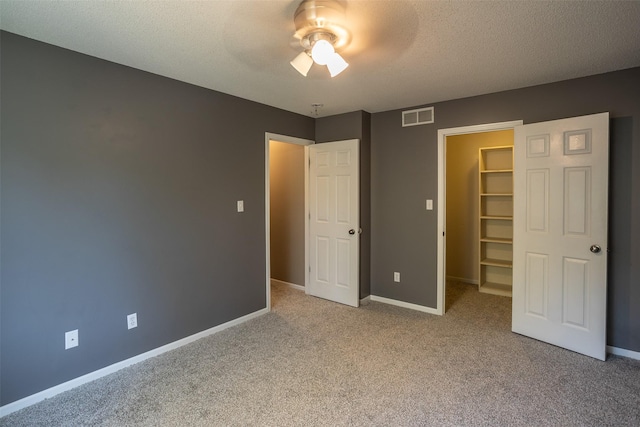 15046 Summit Dr, Clive, IA 50325 - unfurnished bedroom featuring a spacious closet, carpet floors, a closet, a textured ceiling, and a ceiling fan
