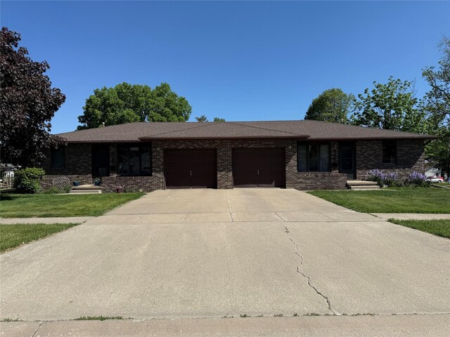 ranch-style house featuring an attached garage, brick siding, driveway, and a front lawn