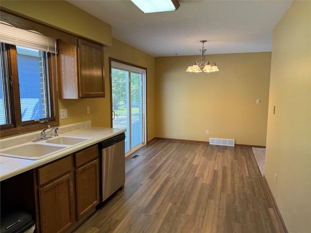 kitchen with dishwasher, a sink, a chandelier, wood finished floors, and light countertops