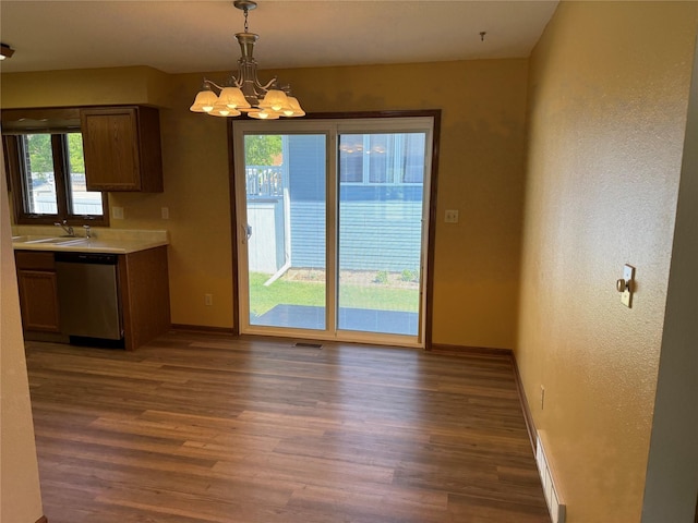 unfurnished dining area with plenty of natural light, wood finished floors, and a chandelier