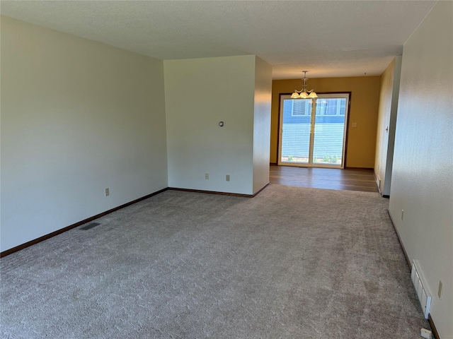 unfurnished room featuring carpet floors, baseboards, and a chandelier