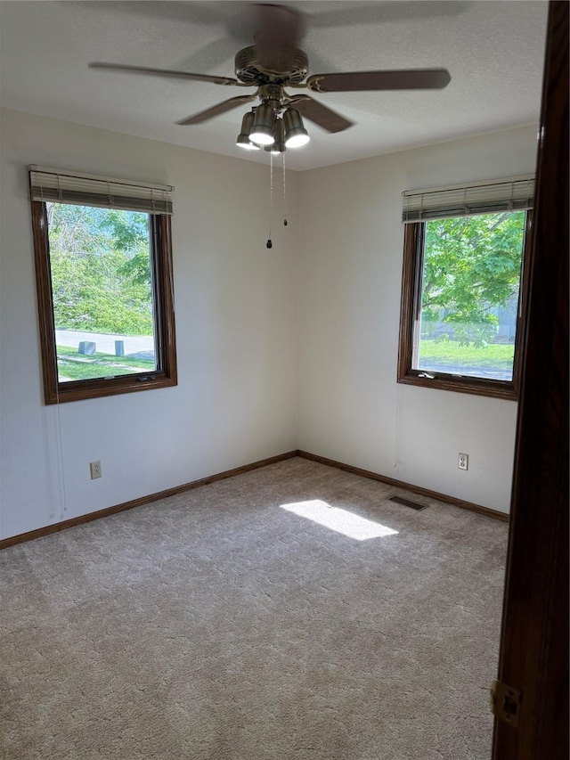 carpeted empty room featuring baseboards and ceiling fan