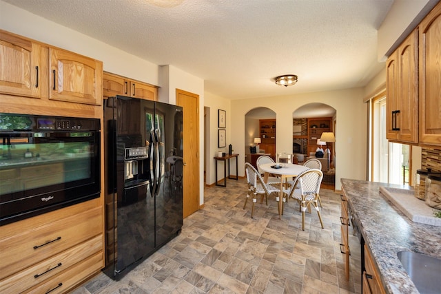 10476 Ricardo Rd, Clive, IA 50325 - kitchen with black appliances, arched walkways, a textured ceiling, and light stone finish floors