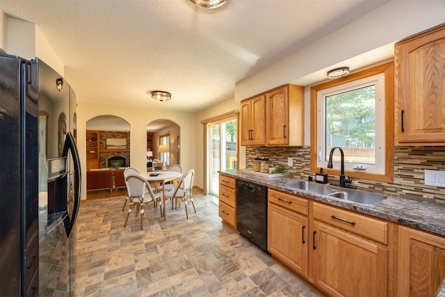 10476 Ricardo Rd, Clive, IA 50325 - kitchen with black appliances, a sink, backsplash, dark countertops, and arched walkways