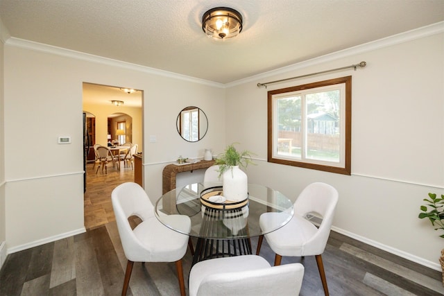 10476 Ricardo Rd, Clive, IA 50325 - dining area featuring arched walkways, wood finished floors, crown molding, baseboards, and a textured ceiling
