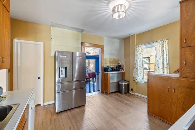 910 Washington St, Eldora, IA 50627 - kitchen with stainless steel fridge, light wood finished floors, light countertops, a sink, and baseboards