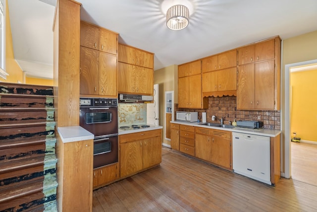 910 Washington St, Eldora, IA 50627 - kitchen with white appliances, under cabinet range hood, light wood-style floors, and tasteful backsplash