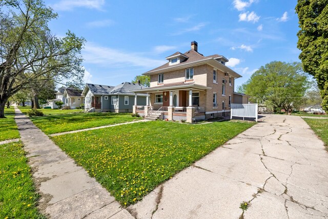 910 Washington St, Eldora, IA 50627 - view of front of home with a porch, a chimney, a front yard, and brick siding
