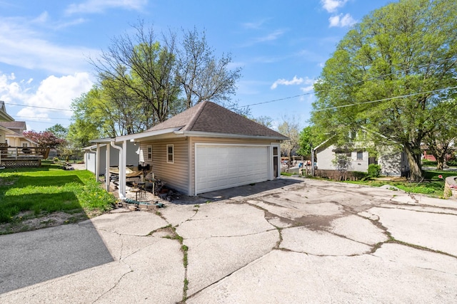 910 Washington St, Eldora, IA 50627 - view of side of home featuring a detached garage, roof with shingles, and a lawn