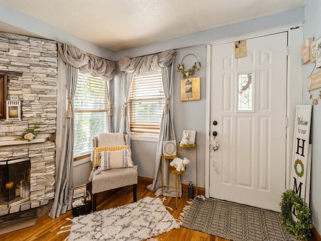 1273 E 18th St, Des Moines, IA 50316 - foyer featuring healthy amount of natural light, wood finished floors, a stone fireplace, and baseboards