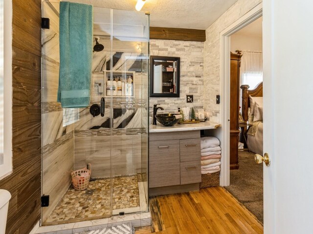 1273 E 18th St, Des Moines, IA 50316 - full bathroom featuring wood finished floors, a stall shower, vanity, and a textured ceiling