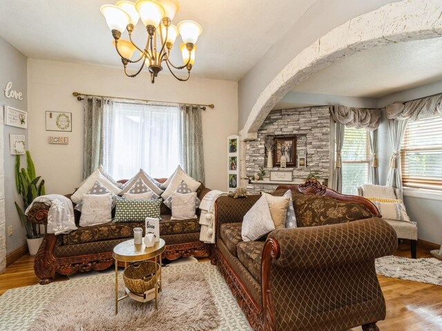 1273 E 18th St, Des Moines, IA 50316 - living room featuring wood finished floors, a chandelier, arched walkways, and baseboards