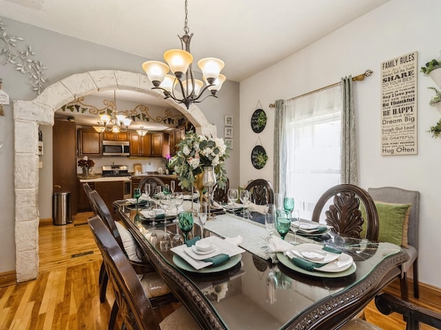 1273 E 18th St, Des Moines, IA 50316 - dining area with a chandelier, light wood-style flooring, and arched walkways