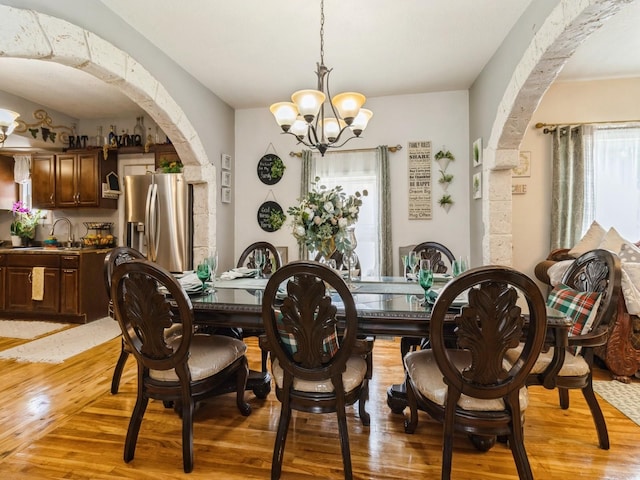 1273 E 18th St, Des Moines, IA 50316 - dining area with arched walkways, light wood-style floors, and a chandelier